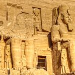 Sculptures of ancient Egyptian Pharaoh carved out of rock with decorative elements representing faces and clothes in sanctuary in Egypt