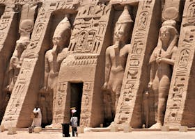 Exterior view of an ancient Egyptian temple featuring hieroglyphics and carved statues.