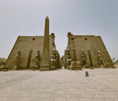 A captivating view of the Karnak Temple with towering obelisks and statues under a clear sky.